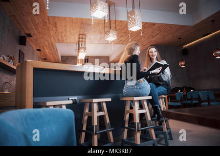 Zwei junge Frauen sitzen im Cafe Kaffee trinken und genießen in gute Bücher. Studenten auf Kaffeepause. Bildung, Lifestyle Konzept Stockfoto