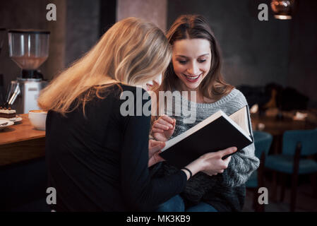 Zwei junge Frauen sitzen im Cafe Kaffee trinken und genießen in gute Bücher. Studenten auf Kaffeepause. Bildung, Lifestyle Konzept Stockfoto