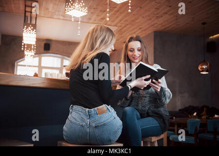 Zwei junge Frauen sitzen im Cafe Kaffee trinken und genießen in gute Bücher. Studenten auf Kaffeepause. Bildung, Lifestyle Konzept Stockfoto