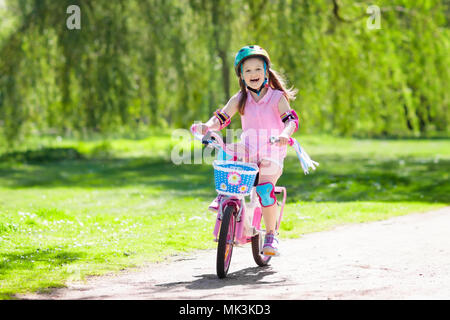 Kind Fahrrad fahren im Sommer Park. Kleines Mädchen lernen ein Fahrrad ohne Stützräder zu fahren. Kindergarten Kind auf zwei Wheeler Fahrrad. Aktive übertreffen Stockfoto