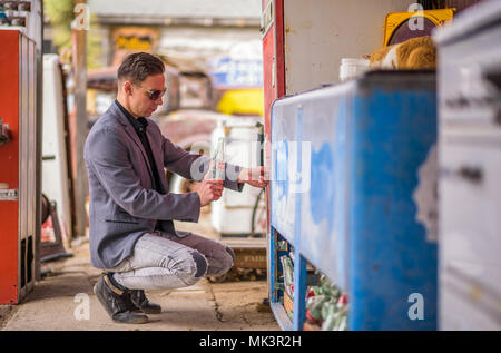 Mann mit einem leeren Coca Cola Flasche an einem Jahrgang Getränkeautomat Stockfoto