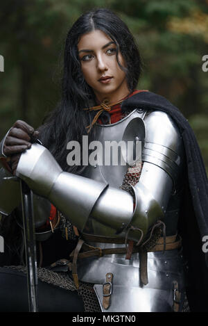 Einen schönen Krieger Mädchen mit einem Schwert tragen Kettenhemden und Rüstung in einen mysteriösen Wald Stockfoto