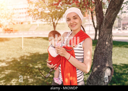 Mutter Kind Baby in wrap Schleuder in Park. Frühling. Konzept der natürlichen parenting glückliche Familie Frühling Konzept Stockfoto