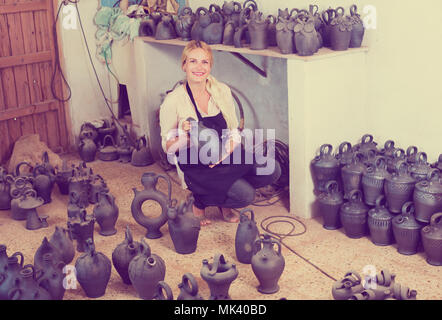 Portrait von fröhlichen weibliche Handwerker mit Schwarz verglaste Keramik Vasen im Atelier Stockfoto