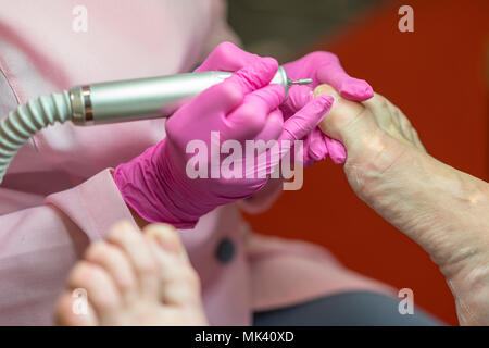 Frau, Füße, Fußpflege. Close up Konzept. Peeling Füße mit speziellen elektrischen Gerät. Fuß Behandlung im Spa Salon. podologie Klinik Stockfoto