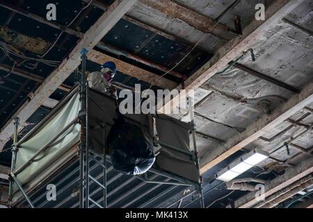 171102-N-QI 061-056 Portsmouth, Virginia (Nov. 2, 2017) der Luftfahrt Bootsmann Mate (Handling) 3. Klasse Theepan Perampalam, Sinajana, Guam, senkt eine Plastiktüte von Gerüsten im Hangar Bay an Bord der Flugzeugträger USS Dwight D. Eisenhower (CVN 69) (IKE). Ike wird derzeit geplante schrittweise Verfügbarkeit (PIA) im Norfolk Naval Shipyard während der Erhaltungsphase der optimiert Flotte Notfallplan (OFRP). (U.S. Marine Foto von Mass Communication Specialist 3. Klasse Nathan T. Bart) Stockfoto