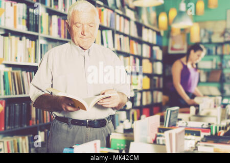 Person 53-64 Jahre alt ist die Wahl Buch zum Lesen in der freien Zeit in der Buchhandlung. Stockfoto