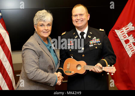 Patty Coffey, US-Armee Korps der Ingenieure Nashville Bezirk Ingenieur, präsentiert eine Ukulele, ein Symbol der Music City, Oberstleutnant Christoph Burkhart, stellvertretender Kommandant, während einer Abschiedszeremonie auf dem Bezirk Hauptsitze in Nashville, Tenn., Nov. 2, 2017. (USACE Foto von Mark Abernathy) Stockfoto