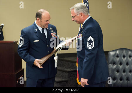 Senior Master Sgt. James Flüsse, Betriebsleiter 123 Intelligence Squadron, präsentiert Chief Master Sgt. Tomi Allinder mit einem Commiserative Gewehr während seiner Pensionierung Zeremonie, Fort Smith, Arche Allinder 33 Jahre in 123 der Arkansas Air National Guard Intelligence Squadron, bevor er als Betriebsleiter, Nov. 04, 2017 serviert. (U.S. Air National Guard Foto von Tech. Sgt. Daniel Condit) Stockfoto