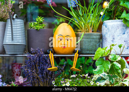 Eine Figur von Humpty Dumpty sitzt auf einem Regal unter Pflanzen und Blumentöpfe außerhalb eines Shop in Kolumbien Road Market, London, UK Stockfoto
