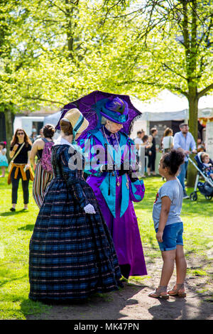 Zwei viktorianischen Damen in einem Garten, mit einem jungen Mädchen an der Fes-Tea-Val 2018 über nationale Kaffee Tag in Chiswick House & Gardens, London, UK stehend Stockfoto