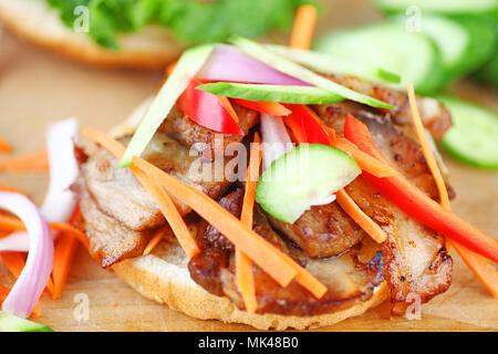 Schweinebraten Schichten mit rohen Gurken, Paprika, Zwiebel und Karotte auf Sesam bun Stockfoto