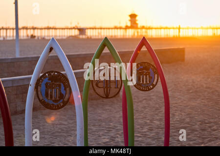 Sonnenlicht hinter dem ikonischen Huntington Beach Pier bei Sonnenuntergang in Huntington Beach, Kalifornien, USA Stockfoto