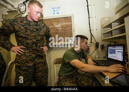 Us Marine 1 Leutnant Matthew Shimp, Links, ein Feld Artillerie Offizier mit Bataillon Landung Team, 2.BATAILLON, 6 Marine Regiment, 26 Marine Expeditionary Unit (MEU), Uhren wie Lance Cpl. Evan J. Beaeudry, ein Feuer Richtung controlman, beteiligt sich an virtuellen Gefechtsfeld III (VBS 3) Ausbildung an Bord der USS Iwo Jima (LHD7), Atlantik, Nov. 7, 2017. VBS 3 ist eine simulierte Programm verwendet taktische Entscheidungsfindung erleichtern, kommunikative Fähigkeiten und die Squad-level Taktik, indem Sie die erweiterte Integration zwischen Artillerie und Beobachter Anruf-für-Feuer zu verbessern. (U.S. Marine Corps Foto von Lan Stockfoto