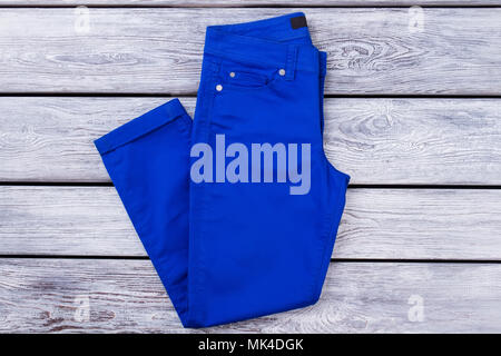 Blau gefaltete Hose. Ansicht von oben, flach. Graue Schreibtisch aus Holz Oberfläche Hintergrund. Stockfoto