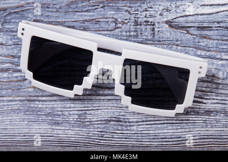 Pixel Sonnenbrille hautnah. Schwarze Brillen mit weißen Rahmen auf hölzernen Schreibtisch Oberfläche. Stockfoto