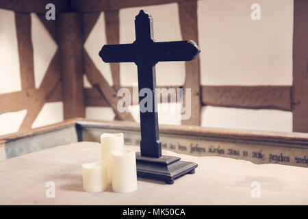 Ein Holzkreuz in einem traditionellen Gebäude symbolisiert Glauben und Spiritualität. Stockfoto