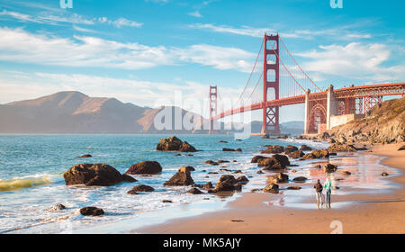 Klassische Panoramablick auf die berühmte Golden Gate Bridge vom malerischen Baker Beach in wunderschönen goldenen Abendlicht gesehen an einem sonnigen Tag mit blauen Himmel und Cl Stockfoto