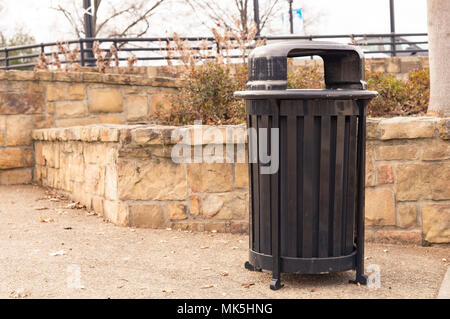 Mülleimer im Park neben dem Stein mauer auf Schotter Gehweg Stockfoto