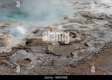 Hell blau Hot Spring mit Dampf durch mineralische Ablagerungen bis steigende umgeben. Stockfoto