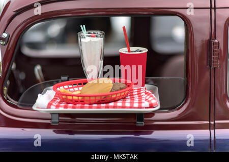 Essen Fach mit Burger Milchshake und Getränk auf Oldtimer am Drive in Movie Theater Stockfoto