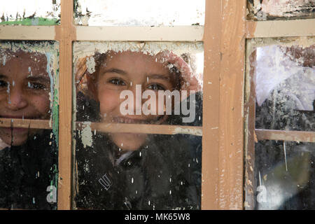 Jungen irakischen Studenten posieren für ein Foto durch eine Schule Fenster an einer Grundschule, Aski Mossul, Irak, Nov. 13, 2017. Die Breite und Vielfalt der Koalitionspartner zeigt die globalen und einheitlichen Ziel der Sieg über ISIS im Irak und in Syrien. CJTF-OIR ist die globale Koalition zu besiegen ISIS im Irak und in Syrien. (U.S. Armee Foto von Sgt. Tracy McKithern) Stockfoto