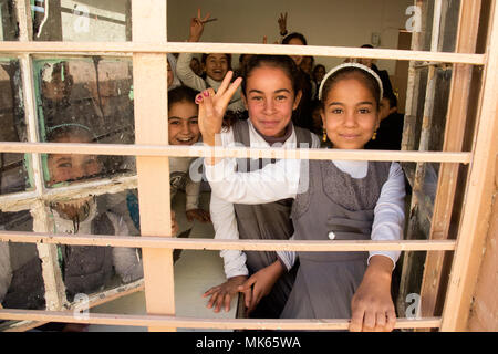 Die irakischen Studenten posieren für ein Foto durch eine Schule Fenster an einer Grundschule, Aski Mossul, Irak, Nov. 13, 2017. Die Breite und Vielfalt der Koalitionspartner zeigt die globalen und einheitlichen Ziel der Sieg über ISIS im Irak und in Syrien. Combined Joint Task Force - inhärenten Lösen, die globale Koalition zu besiegen ISIS im Irak und in Syrien. (U.S. Armee Foto von Sgt. Tracy McKithern) Stockfoto