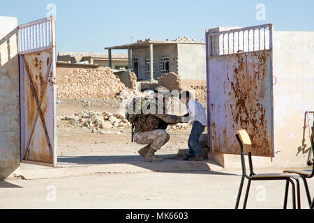 Eine italienische Armee Soldat 3. Alpine Regiment zugeordnet, eingesetzt zur Unterstützung der Operation inhärenten Lösen, und einem irakischen Terrorismus Service Mitglied kitzelt Ein irakischer Student an einer Grundschule im Dorf von Babinet, Irak, Nov. 14, 2017. Die Breite und Vielfalt der Koalitionspartner zeigt die globalen und einheitlichen Ziel der Sieg über ISIS im Irak und in Syrien. CJTF-OIR ist die globale Koalition zu besiegen ISIS im Irak und in Syrien. (U.S. Armee Foto von Sgt. Tracy McKithern) Stockfoto