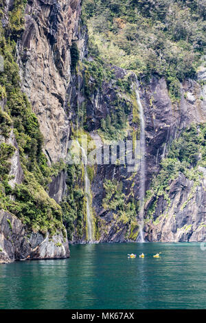 MILFORD SOUND, Neuseeland - 14. NOVEMBER 2017: Kajakfahrer die Landschaft und die Wasserfälle von Milford Sound, eine der populärsten Touristenattraktionen in Neuseeland genießen Stockfoto