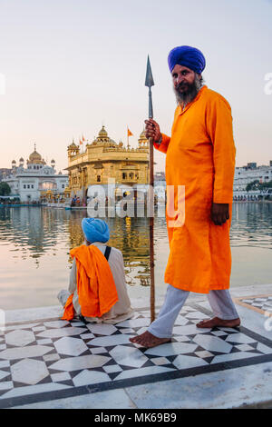Amritsar, Punjab, Indien: ein Sikh guard bewaffnet mit einem Speer an der Amrit Sarovar (Pool von Nektar) und dem Goldenen Tempel. Stockfoto