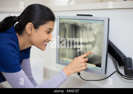 Closeup Portrait von Alliierten zahnmedizinische Heilberufe in blau scheuert Prüfung Zahnröntgen auf Bildschirm, isolierte Zahnarztpraxis Stockfoto