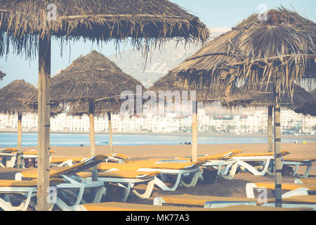 Strandliegen und Sonnenschirme am Meer. Main Beach in Agadir Stadt an der Küste des Atlantischen Ozeans. Marokko entfernt. Stockfoto
