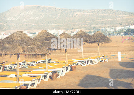 Strandliegen und Sonnenschirme am Meer. Main Beach in Agadir Stadt an der Küste des Atlantischen Ozeans. Marokko entfernt. Stockfoto