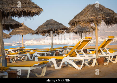 Strandliegen und Sonnenschirme am Meer. Main Beach in Agadir Stadt an der Küste des Atlantischen Ozeans. Marokko entfernt. Stockfoto