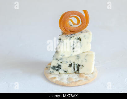 Blauschimmelkäse auf Cracker mit getrockneten Aprikosen Obst Dekoration auf weißem Hintergrund curl Stockfoto