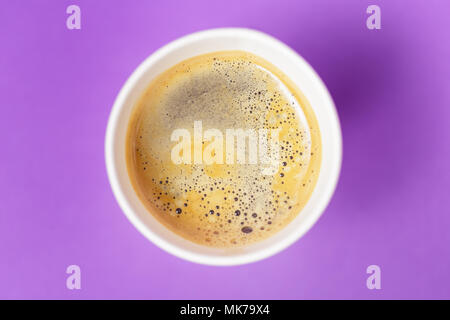 Blick von oben auf die take-out heißen Getränk in geöffnet thermo Tasse auf lebhaften violetten Hintergrund. Cafe Crema Schaum auf dem americano Kaffee Stockfoto