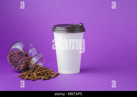 Nehmen Sie ein heißes Getränk in geschlossenen Pappbecher, Kaffeebohnen aus Glas auf lebhaften violetten Hintergrund verstreut Stockfoto