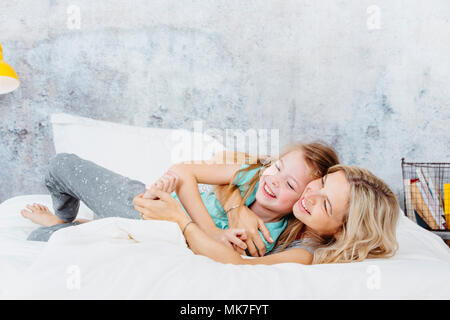 Schönen Mutter und Tochter im Bett kuscheln Stockfoto