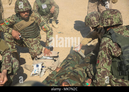 Nationale afghanische Armee Soldaten mit 6 Kandak, 1. Brigade, 215 Corps medizinische Versorgung zu einer fiktiv verletzten Soldaten bei Unfall Evakuierungsübung im Camp Shorabak, Afghanistan, 19.11.2017. Als Teil der Betriebsbereitschaft Zyklus, afghanische Ausbilder im Helmand regionalen militärischen Training Center hielt die erste Iteration der CASEVAC Ausbildung während der 2-monatigen Kurs, um zu helfen, seine Studenten für Operationen gegen die Taliban vorzubereiten. Us-Berater für mehrere Schulen zugewiesen, beraten, unterstützen Befehle aus ganz Afghanistan beobachtet, um die Simulation zu standardisierten implementieren Stockfoto