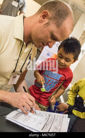 Us-Armee finden Sgt. Brendan Irland, ein optometrie Techniker, geht über einen Vision-fitness test mit Justin Vasquez, 3, in der Betreuung Hafen in Los Angeles, Calif., Nov. 18, 2017. Irland, ist eines von Dutzenden von Armee-reserve Soldaten aus der 7214Th medizinische Unterstützung in Los Alamitos, Calif., stationiert, die ihre Zeit und ihren medizinischen Know-how freiwillig helfen Kostenlose Versorgung für die Bürger von Los Angeles bieten; viele von ihnen haben keinen Zugang zu medizinischer Versorgung. (U.S. Armee Foto: Staff Sgt. Felix R. Fimbres) Stockfoto