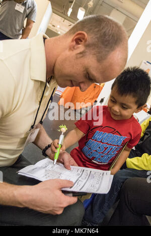 Us-Armee finden Sgt. Brendan Irland, ein optometrie Techniker, geht über einen Vision-fitness test mit Justin Vasquez, 3, in der Betreuung Hafen in Los Angeles, Calif., Nov. 18, 2017. Irland, ist eines von Dutzenden von Armee-reserve Soldaten aus der 7214Th medizinische Unterstützung in Los Alamitos, Calif., stationiert, die ihre Zeit und ihren medizinischen Know-how freiwillig helfen Kostenlose Versorgung für die Bürger von Los Angeles bieten; viele von ihnen haben keinen Zugang zu medizinischer Versorgung. (U.S. Armee Foto: Staff Sgt. Felix R. Fimbres) Stockfoto