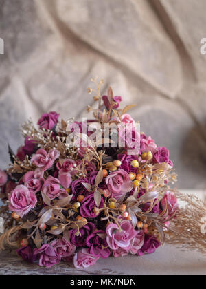 Blumenstrauß Vintage künstliche Rose Blumen auf Gewebe und Stein Stockfoto