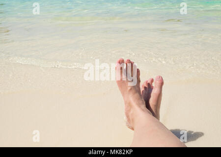 Nahe stützen Reisenden Kreuz barfuß Bein legen am Strand am Meer, relaxen im Sommer Urlaub. Stockfoto