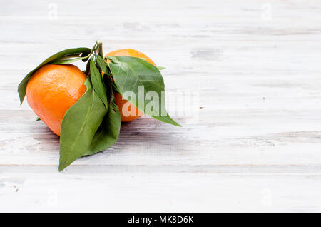 Frische rohe organische Tangerinen Clementine mit grünen Blättern auf weissem Holztisch., kopieren Raum Stockfoto
