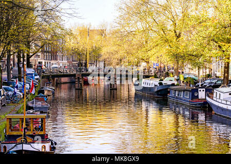 Blick auf wunderschöne Amsterdam, Hauptstadt der Niederlande, mit Kanälen, canalboats, Bäume und Reflexionen im Wasser Stockfoto