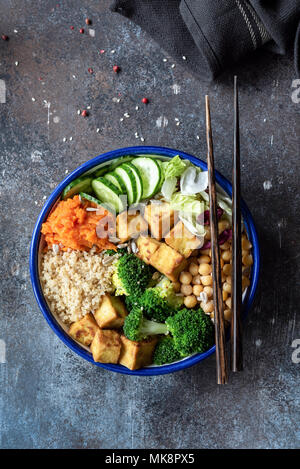 Salat mit Quinoa, Tofu, Brokkoli, Kichererbsen und Gemüse. Buddha Schüssel auf dunklem Hintergrund. Bunte vegetarische Buddha Schüssel. Nähren Salatschüssel, Tabl Stockfoto