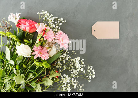 Blumenstrauß aus rosa und weißen Blüten auf grauem Hintergrund mit einer Karte für Muttertag Stockfoto