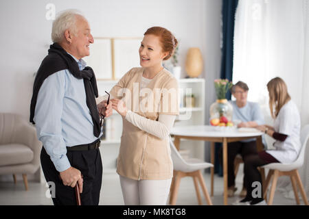 Ausschreibung die Aufmerksamkeit des medizinischen Personals gegenüber älteren Mann und Frau, Reden, erklären, tröstlich in Luxury Care facility gemeinsame Zimmer Stockfoto