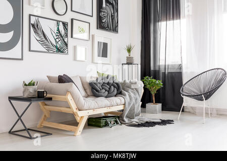 Sessel neben Holz- Sofa im Gegensatz Wohnzimmer mit Galerie der Poster Stockfoto