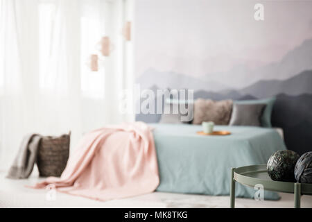 Dekorative Kugeln am grünen Tisch im gemütlichen Schlafzimmer Innenraum mit rosa Decke auf dem Bett Stockfoto